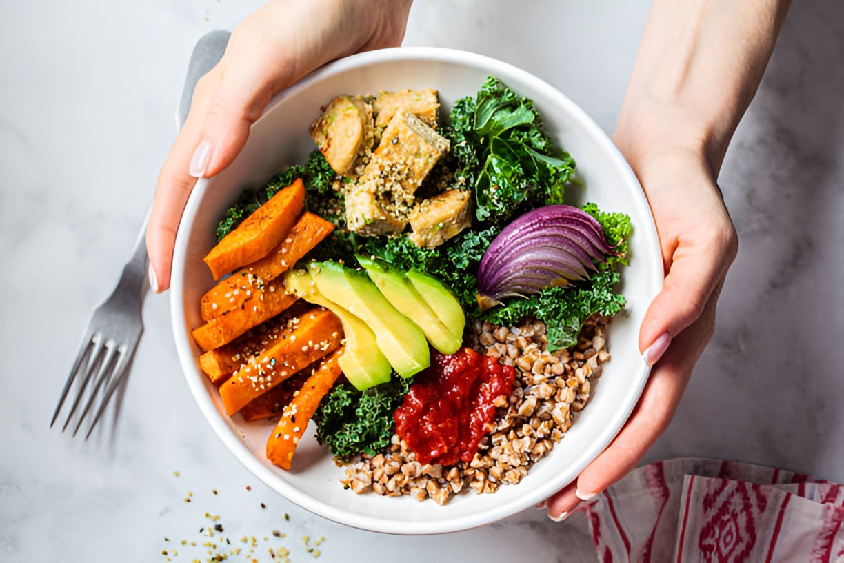 woman holding a bowl of buckwheat topped with vegetables and fruits